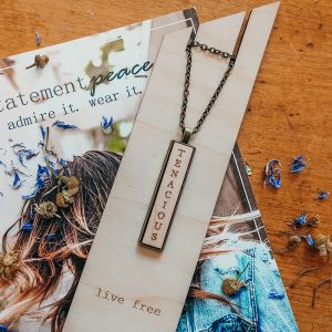 wooden necklace that reads tenacious