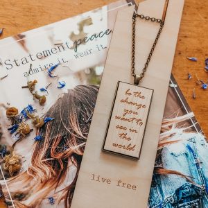 a wood necklace that reads be the change you want to see in the world