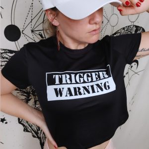 girl in white hat wearing black cropped tee reading trigger warning